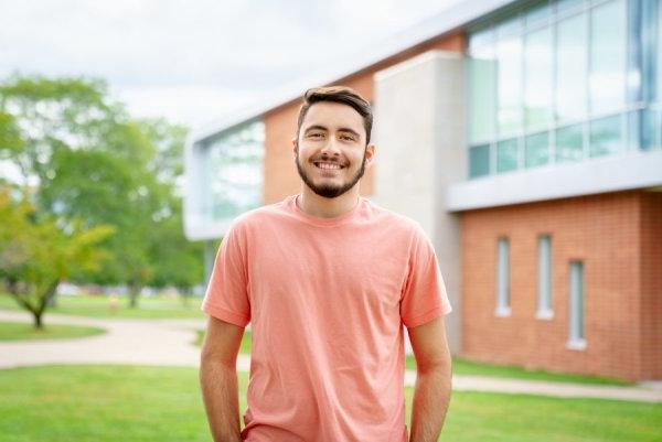 Communication and Media major and Editor-in_chief of The Tangerine, Matthew Breault, stands on campus, smiling at camera.